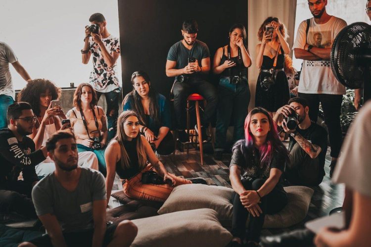 Photo by Matheus Bertelli Group of multiethnic young people wearing casual clothes gathering together in spacious studio and listening attentively to female speaker